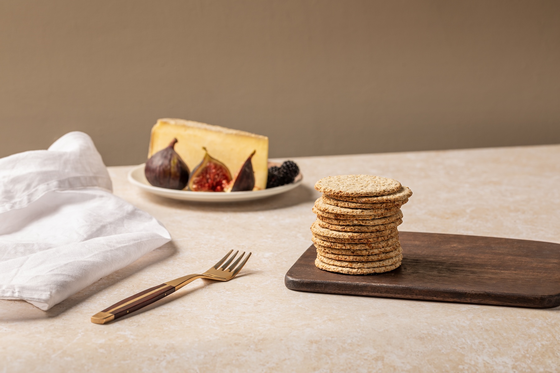 Stack of oatcakes with cheese and figs in background